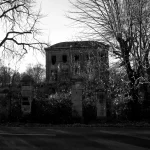 A dark, monochrome photograph depicting a building. The first image in the "Places That Time Forgot" series, titled "Scraps-of-Love".