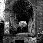 A dark, monochrome photograph depicting the entrance hall of a building. The second image in the "Places That Time Forgott" series, titled "Passage-to-the-Past".